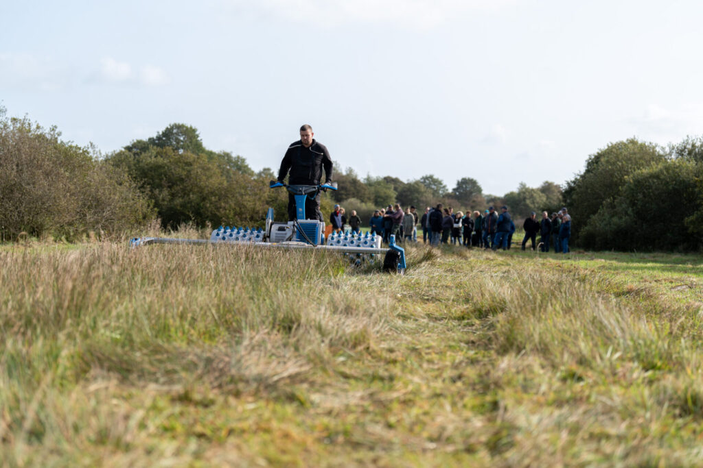 Paludikultur auf der Klimafarm in Schleswig-Holstein: Ein Bauer mäht Gräser mit einem Balkenmäher.