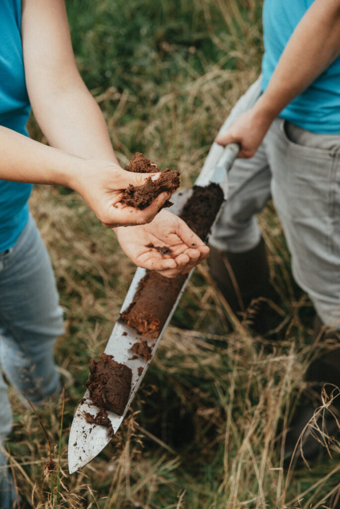 Zwei Menschen nehmen eine Bodenprobe im Moor.