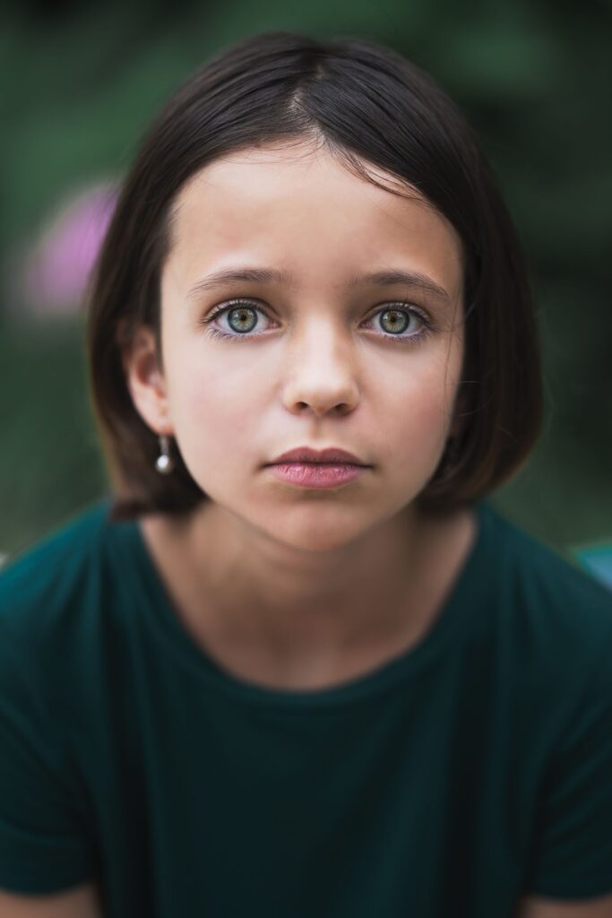 Pensive little girl in casual t shirt with short hair looking at camera